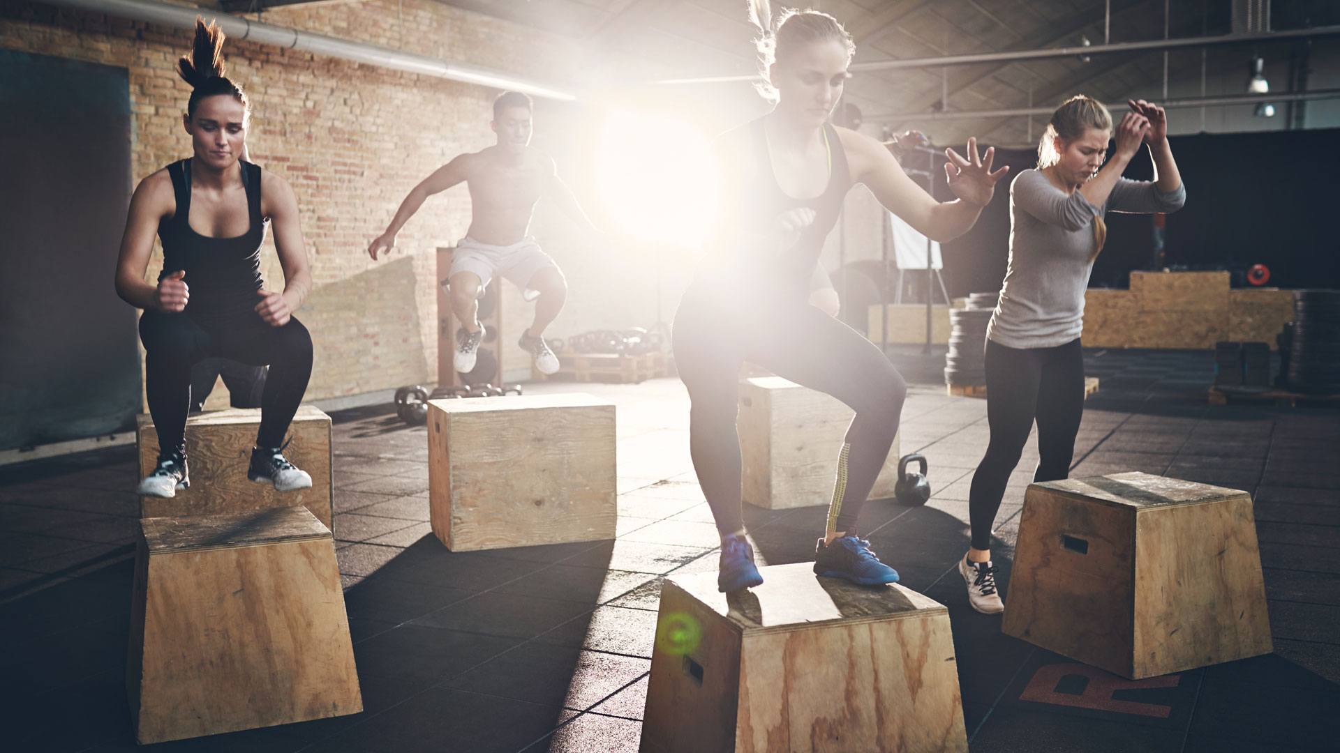 Four athletes perform box jumps. 